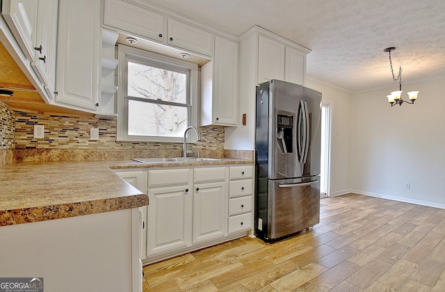 kitchen with pendant lighting, sink, white cabinets, stainless steel fridge with ice dispenser, and decorative backsplash