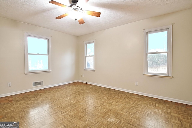 spare room featuring light parquet floors, ceiling fan, and a textured ceiling