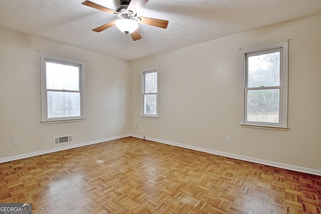 unfurnished room featuring light parquet floors, ceiling fan, and a textured ceiling