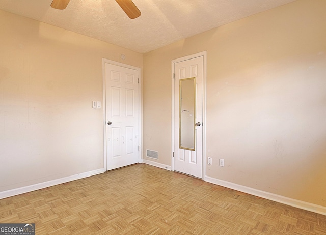 spare room featuring light parquet flooring, ceiling fan, and a textured ceiling