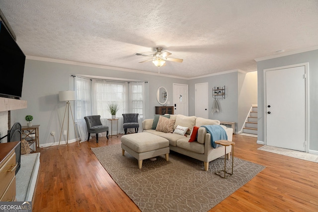 living room featuring wood-type flooring, a textured ceiling, ceiling fan, and crown molding