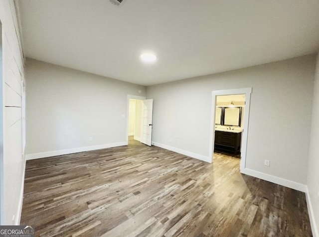 unfurnished bedroom with wood-type flooring and ensuite bathroom