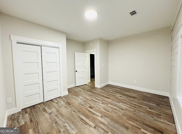 unfurnished bedroom featuring wood-type flooring and a closet