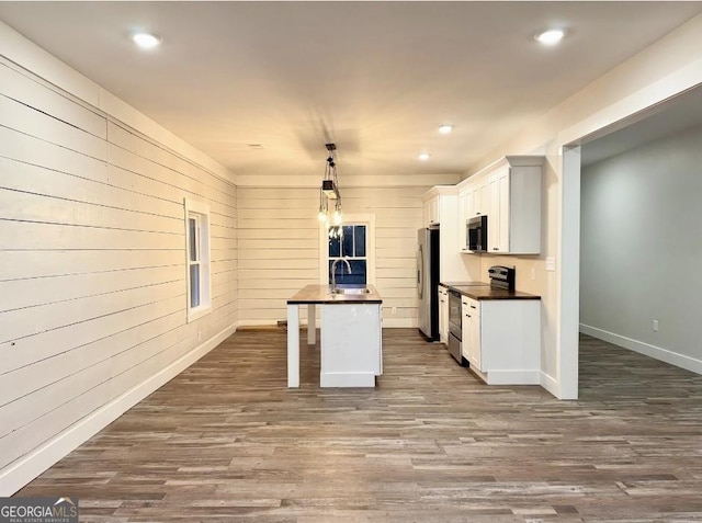 kitchen with white cabinets, hanging light fixtures, appliances with stainless steel finishes, and dark wood-type flooring