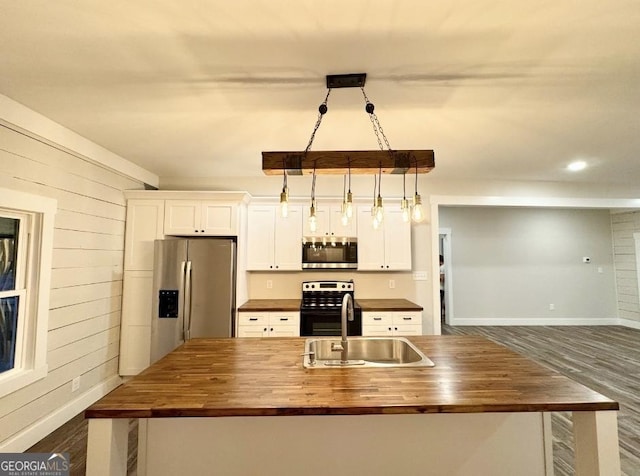 kitchen with white cabinets, appliances with stainless steel finishes, and butcher block counters