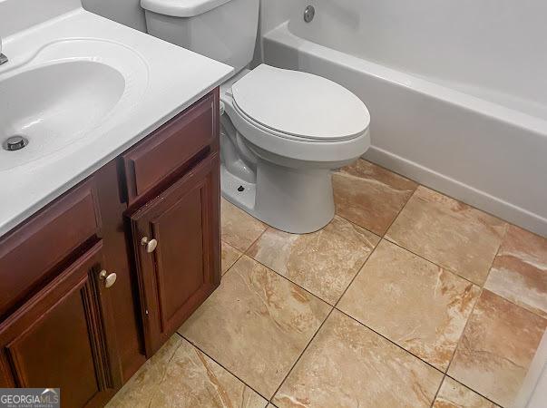 bathroom featuring tile patterned flooring, vanity, a tub to relax in, and toilet