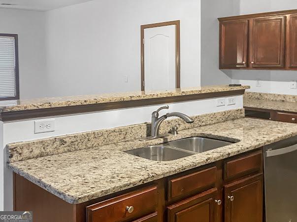 kitchen with dishwasher, sink, and light stone counters