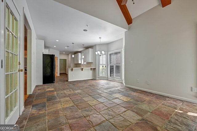 unfurnished living room with vaulted ceiling with beams and an inviting chandelier