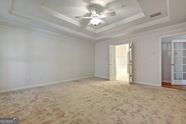 carpeted empty room featuring a tray ceiling, ceiling fan, french doors, and ornamental molding