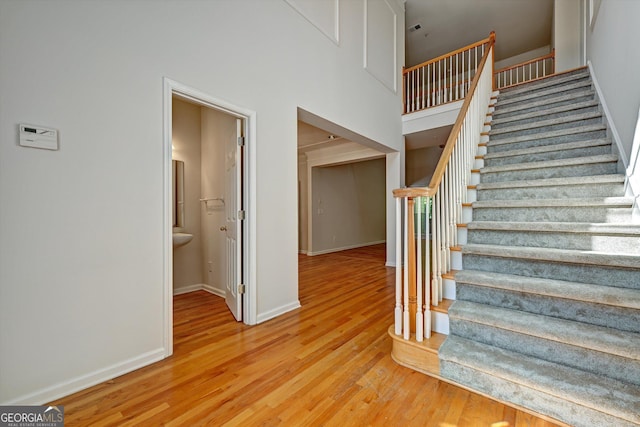 stairs with hardwood / wood-style floors and a high ceiling