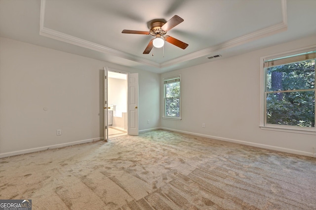 unfurnished room featuring a raised ceiling, ceiling fan, light carpet, and ornamental molding