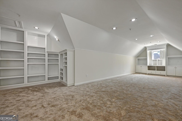 additional living space featuring carpet flooring, built in shelves, and lofted ceiling