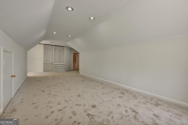 additional living space featuring light colored carpet and vaulted ceiling