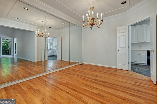 unfurnished dining area with a chandelier, crown molding, and light hardwood / wood-style flooring