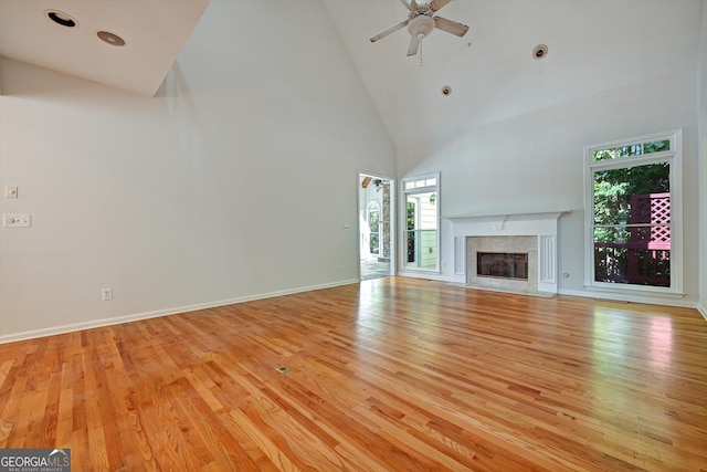 unfurnished living room featuring ceiling fan, light wood-type flooring, and high vaulted ceiling