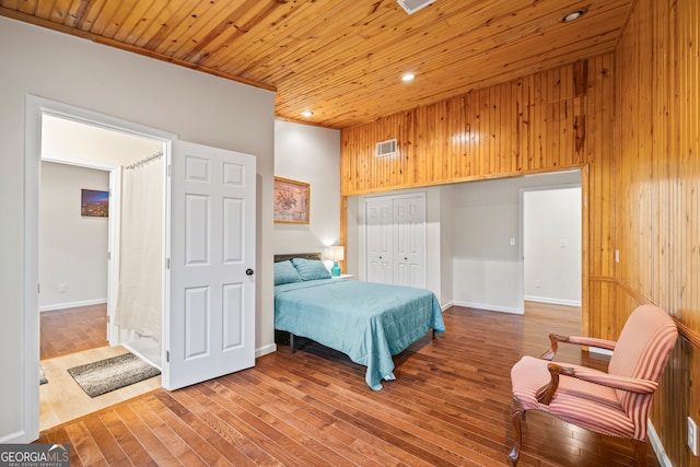 bedroom featuring crown molding, wooden walls, wooden ceiling, hardwood / wood-style floors, and a closet