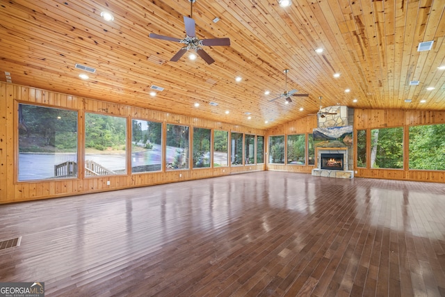 unfurnished living room featuring hardwood / wood-style floors, a healthy amount of sunlight, and wood walls