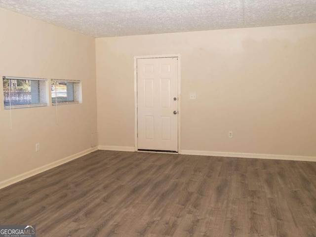 spare room with a textured ceiling and dark hardwood / wood-style floors