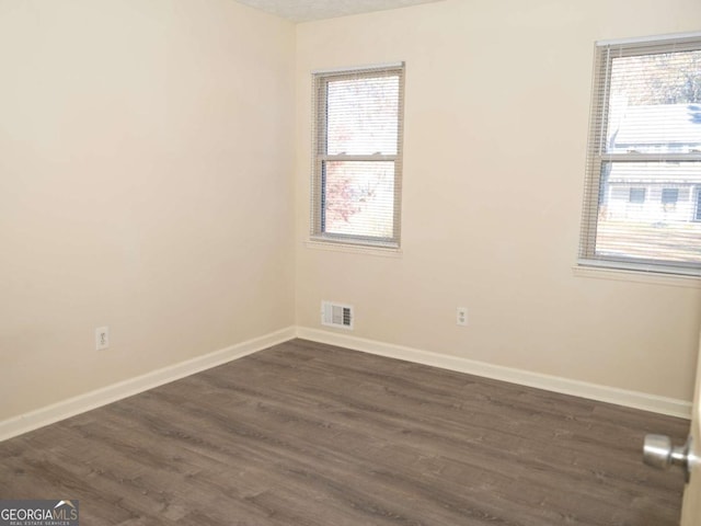 spare room with a textured ceiling and dark hardwood / wood-style floors