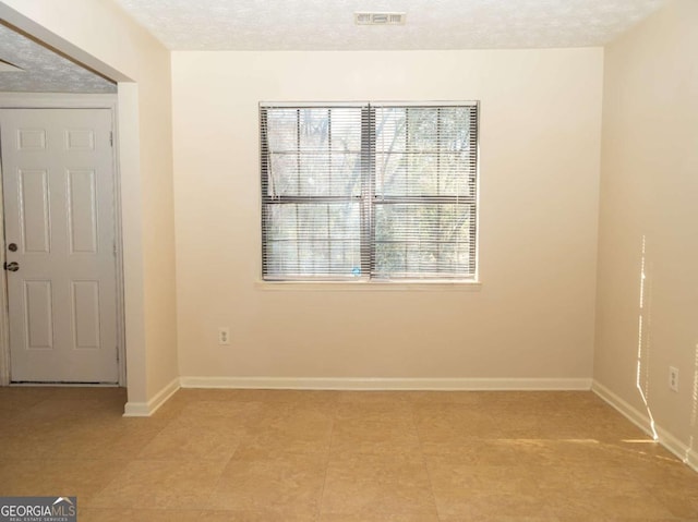 tiled empty room with a textured ceiling