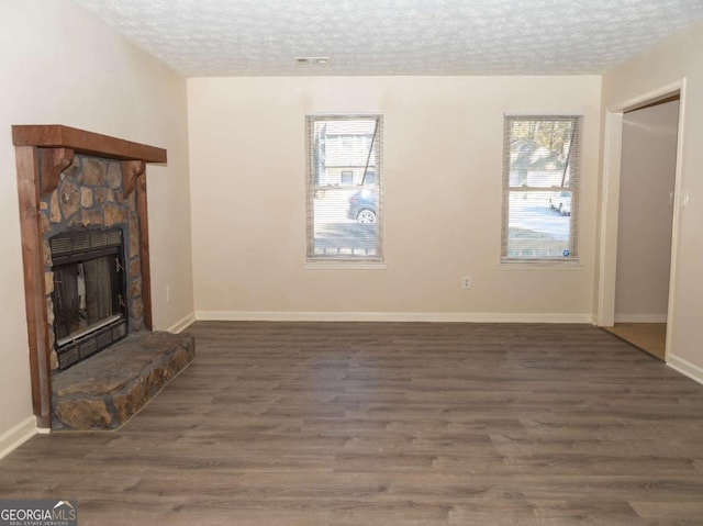 unfurnished living room with a textured ceiling, a fireplace, and dark wood-type flooring