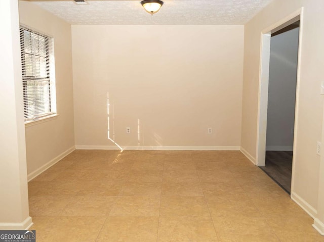 empty room featuring light tile patterned floors and a textured ceiling