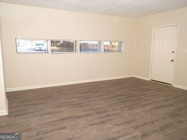 empty room featuring a textured ceiling and dark hardwood / wood-style floors