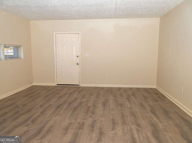 empty room featuring a textured ceiling and dark hardwood / wood-style floors