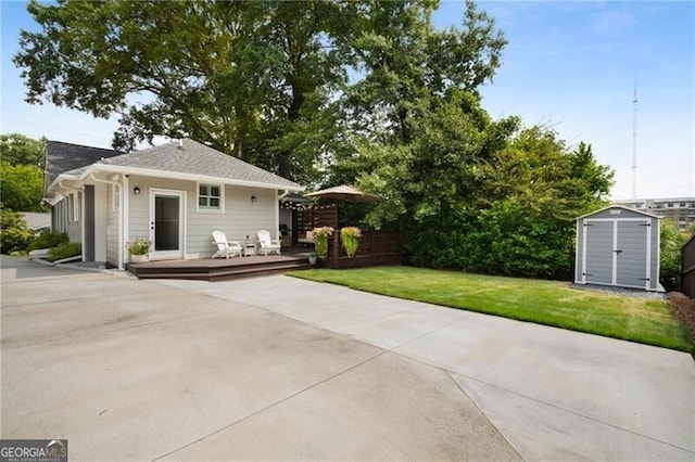 rear view of property with a yard, a deck, and a storage unit