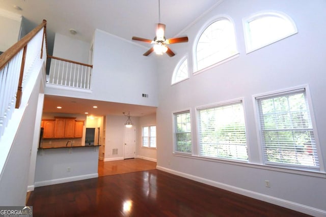 unfurnished living room featuring ornamental molding, a healthy amount of sunlight, and a high ceiling