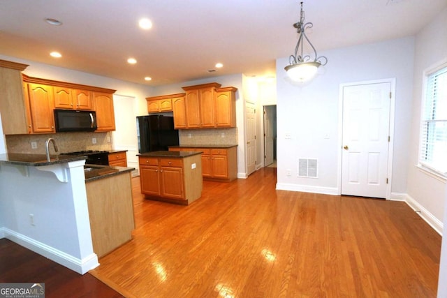 kitchen featuring hanging light fixtures, a healthy amount of sunlight, black refrigerator, and a center island