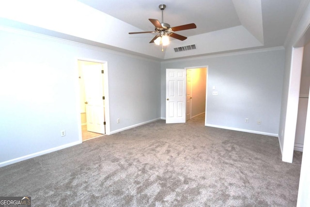 unfurnished bedroom featuring ornamental molding, a raised ceiling, carpet flooring, ceiling fan, and ensuite bathroom