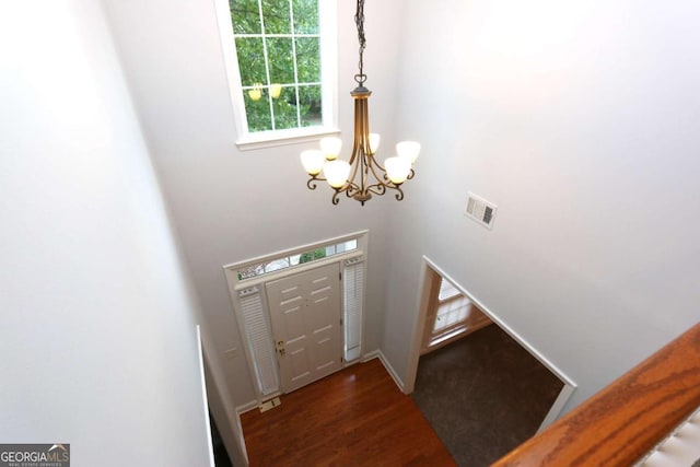 entryway with a high ceiling, dark wood-type flooring, and a notable chandelier