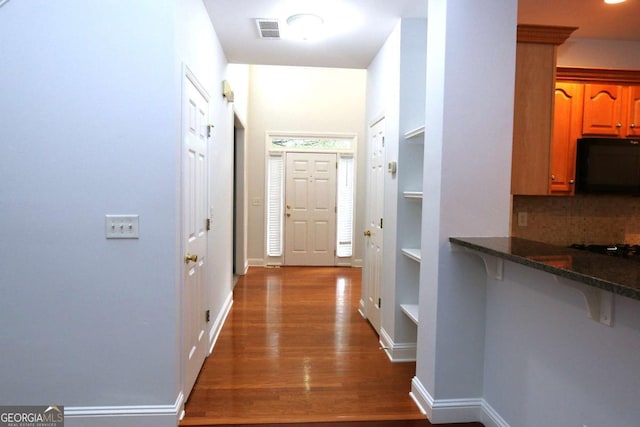 corridor with dark wood-type flooring and built in shelves