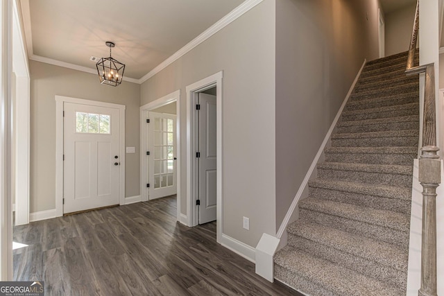 entrance foyer featuring dark hardwood / wood-style flooring, ornamental molding, and an inviting chandelier