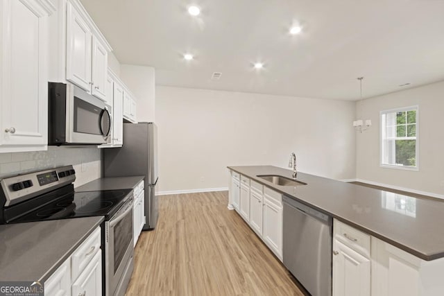 kitchen with white cabinetry, sink, stainless steel appliances, light hardwood / wood-style flooring, and a notable chandelier