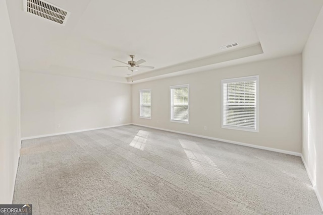 carpeted spare room featuring a tray ceiling and ceiling fan