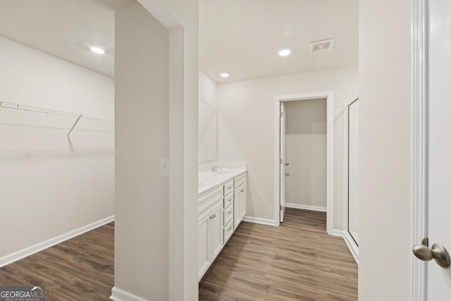 bathroom with hardwood / wood-style floors, vanity, and walk in shower