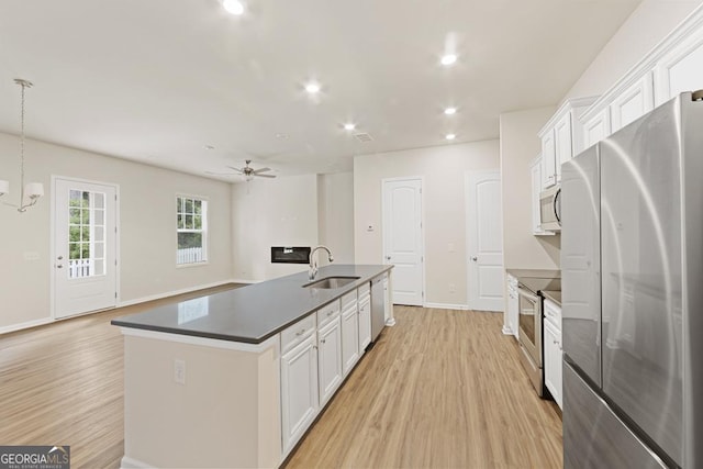 kitchen with sink, stainless steel appliances, decorative light fixtures, a center island with sink, and white cabinets