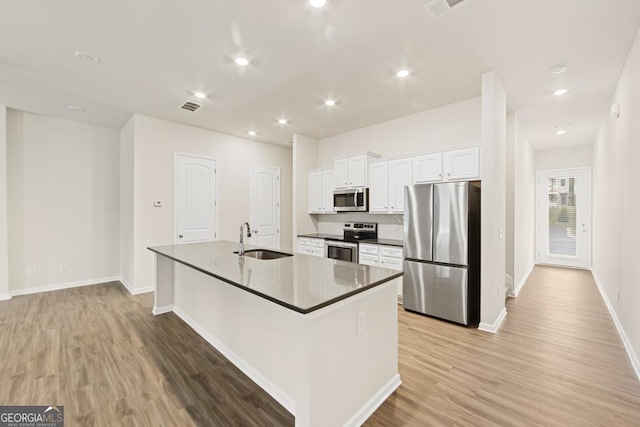 kitchen with sink, stainless steel appliances, light hardwood / wood-style flooring, an island with sink, and white cabinets