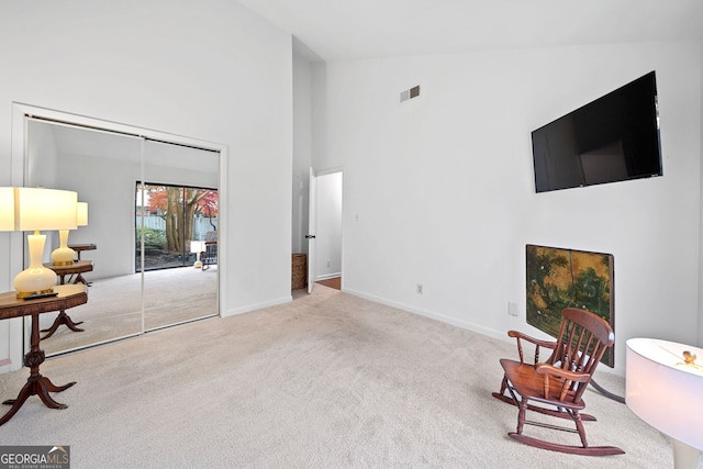 sitting room with light colored carpet and high vaulted ceiling