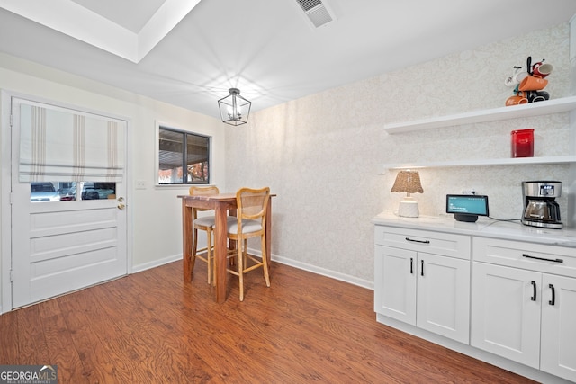 kitchen with wood-type flooring, white cabinetry, a notable chandelier, and light stone counters