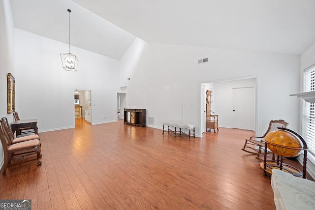 sitting room with an inviting chandelier, hardwood / wood-style flooring, and high vaulted ceiling