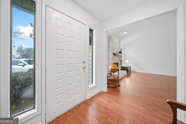 entryway with a stone fireplace, a wealth of natural light, and hardwood / wood-style flooring