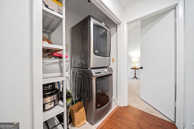 washroom with hardwood / wood-style floors and stacked washer and dryer