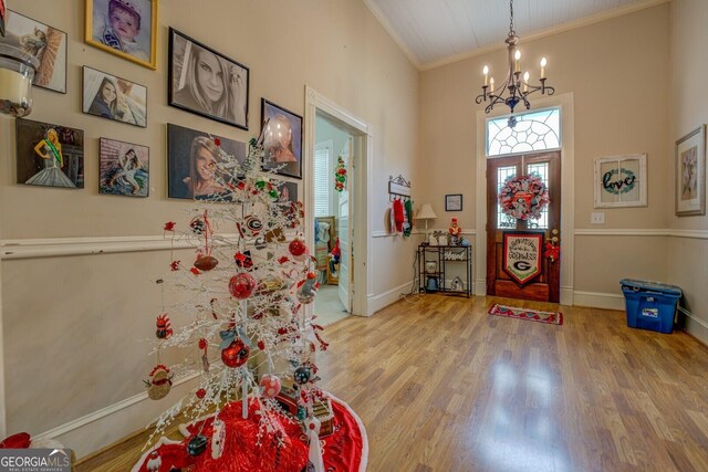 foyer with a chandelier, hardwood / wood-style floors, a towering ceiling, and crown molding