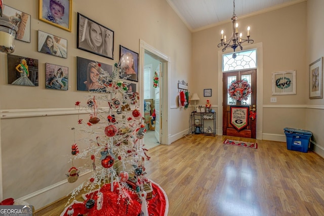 foyer entrance featuring a chandelier, lofted ceiling, wood finished floors, baseboards, and crown molding