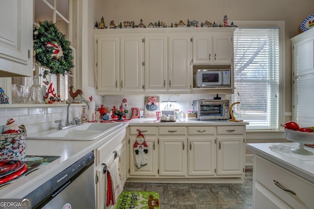 kitchen with a toaster, light countertops, white microwave, a sink, and dishwasher