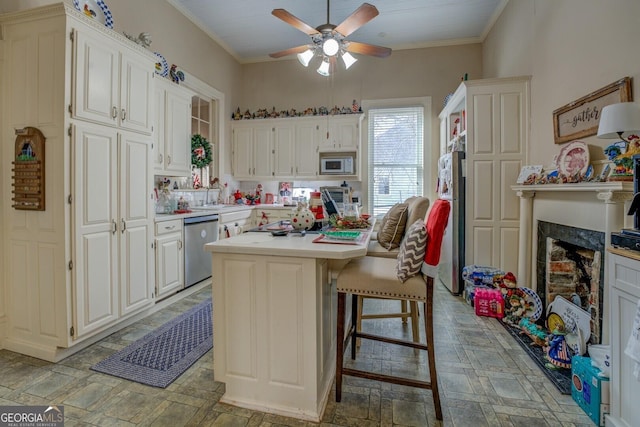 kitchen featuring white microwave, stone finish flooring, light countertops, crown molding, and stainless steel dishwasher