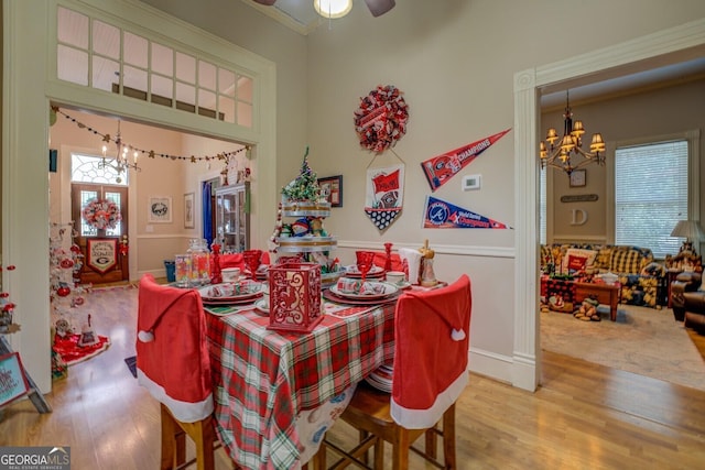 dining space with crown molding, wood-type flooring, and ceiling fan with notable chandelier